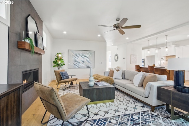 living room with recessed lighting, light wood finished floors, ceiling fan, and a fireplace