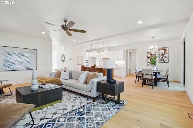 living area featuring recessed lighting, baseboards, light wood-style flooring, and ceiling fan with notable chandelier