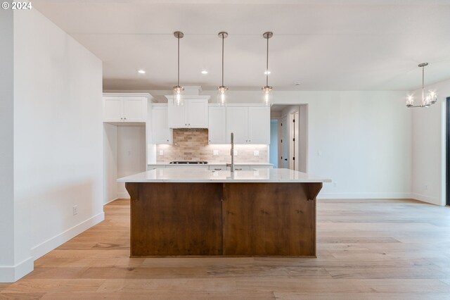 kitchen with a center island with sink, black gas cooktop, white cabinets, and hanging light fixtures