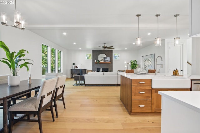 kitchen with pendant lighting, brown cabinets, light countertops, recessed lighting, and light wood-style flooring