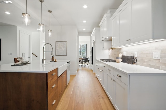 kitchen with a sink, light wood finished floors, stainless steel appliances, recessed lighting, and backsplash