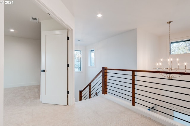 hall with a notable chandelier and light colored carpet