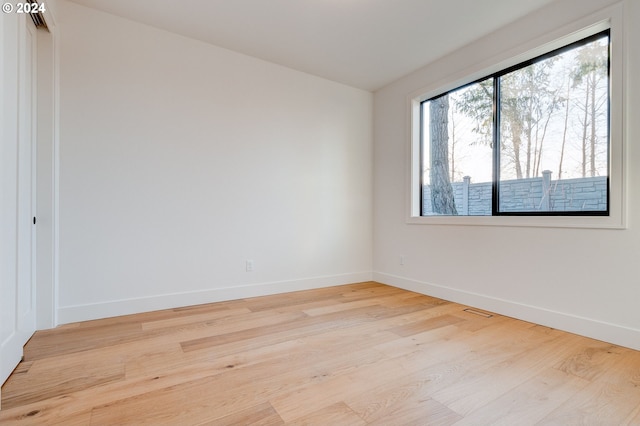 unfurnished room featuring baseboards, visible vents, and wood finished floors