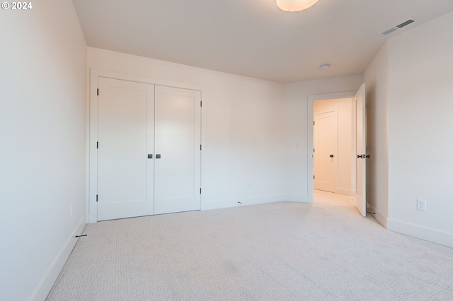 unfurnished bedroom with baseboards, visible vents, light carpet, and a closet