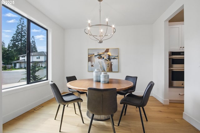 dining space with baseboards, light wood finished floors, a notable chandelier, and a healthy amount of sunlight