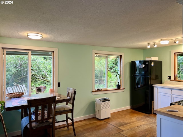 kitchen with black fridge, white cabinetry, light hardwood / wood-style flooring, and plenty of natural light