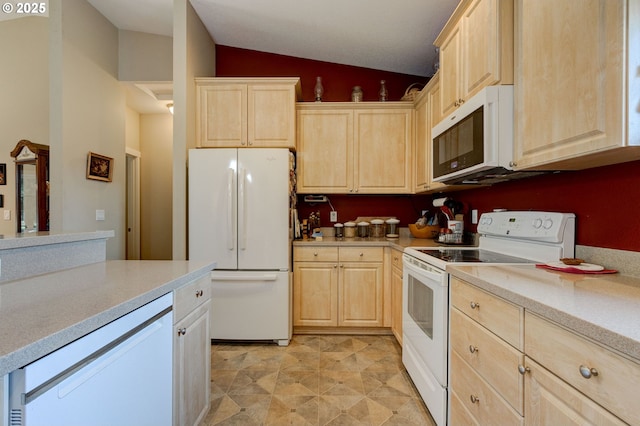 kitchen with white appliances, light brown cabinetry, and vaulted ceiling