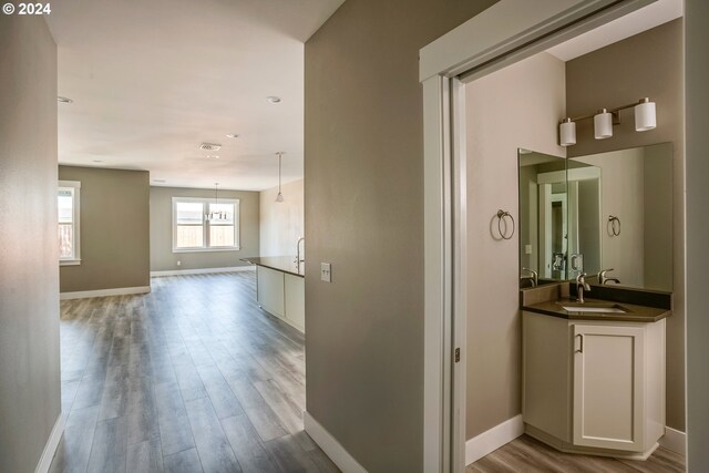 corridor with light hardwood / wood-style floors and sink