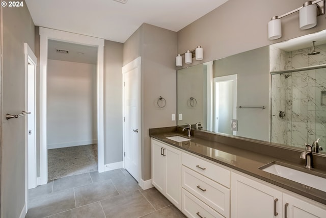 bathroom with dual vanity, a shower with shower door, and tile patterned flooring