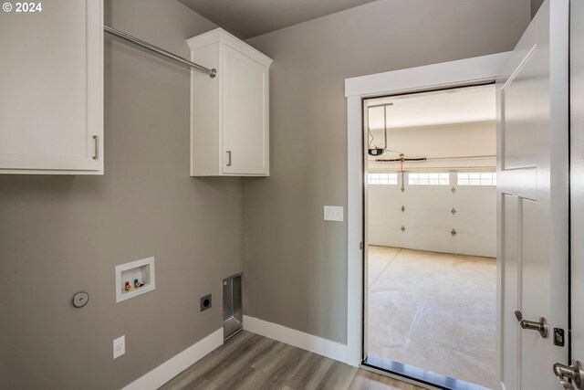 laundry area with washer hookup, light hardwood / wood-style floors, electric dryer hookup, and cabinets