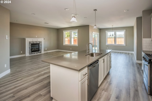 kitchen featuring sink, stainless steel dishwasher, light wood-type flooring, and an island with sink