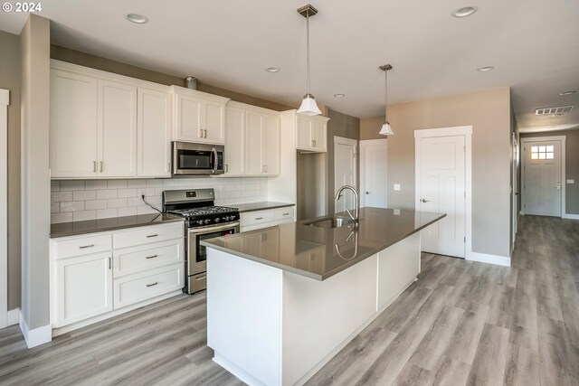 kitchen with stainless steel appliances, a center island with sink, sink, light hardwood / wood-style floors, and white cabinetry