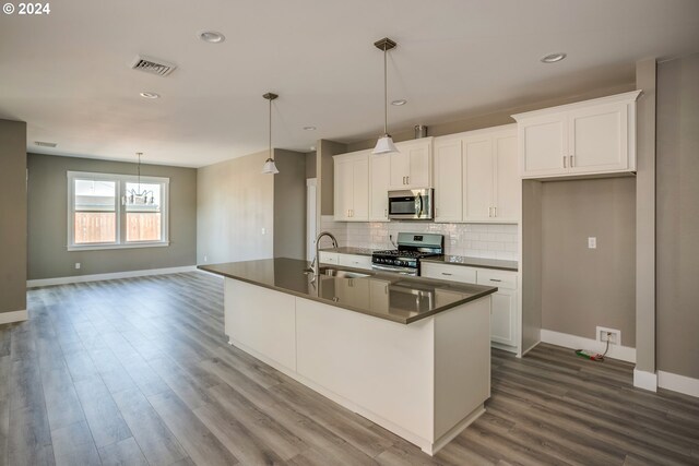 kitchen with hardwood / wood-style floors, a kitchen island with sink, appliances with stainless steel finishes, and sink