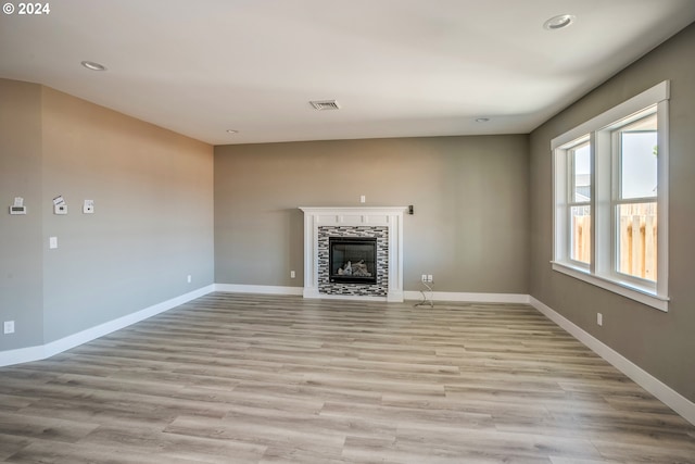 unfurnished living room featuring light hardwood / wood-style flooring and a tiled fireplace