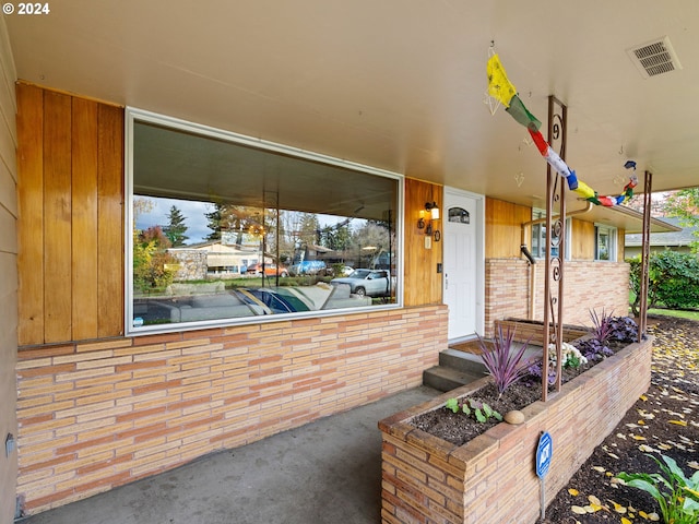 doorway to property featuring visible vents and brick siding