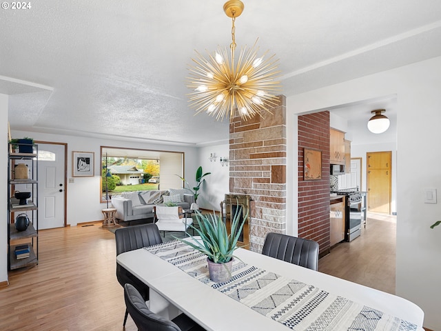 dining area featuring a chandelier, a textured ceiling, and light wood-style floors