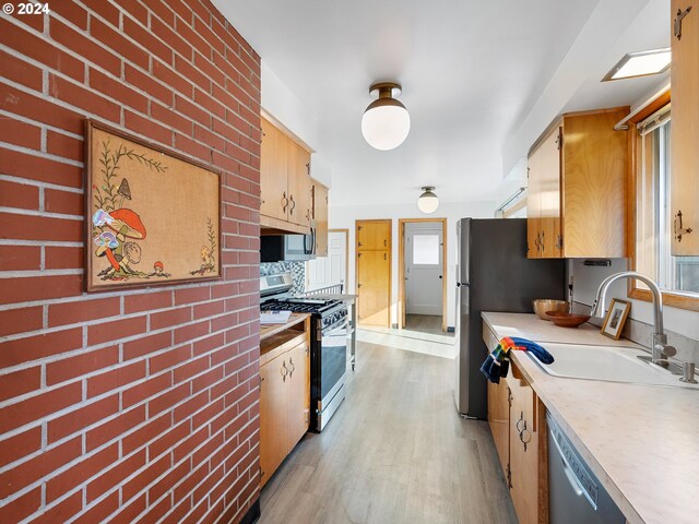 kitchen with light hardwood / wood-style floors, brick wall, sink, and appliances with stainless steel finishes