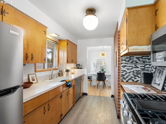 kitchen with stainless steel appliances, a sink, light countertops, backsplash, and brown cabinetry