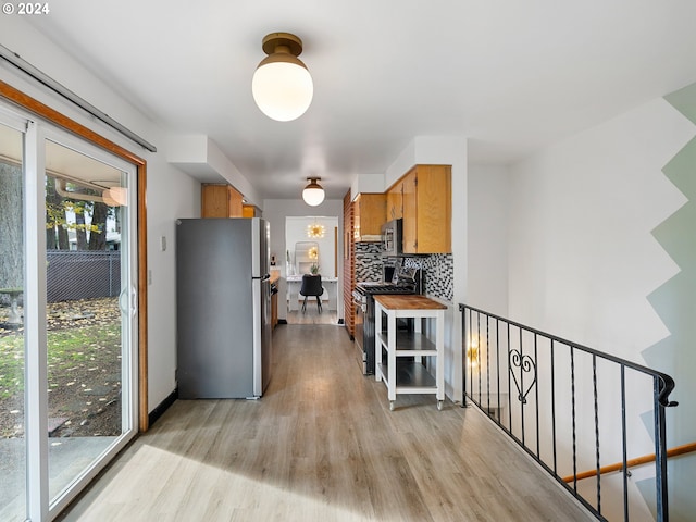 kitchen with brown cabinets, light wood-style flooring, stainless steel appliances, and decorative backsplash