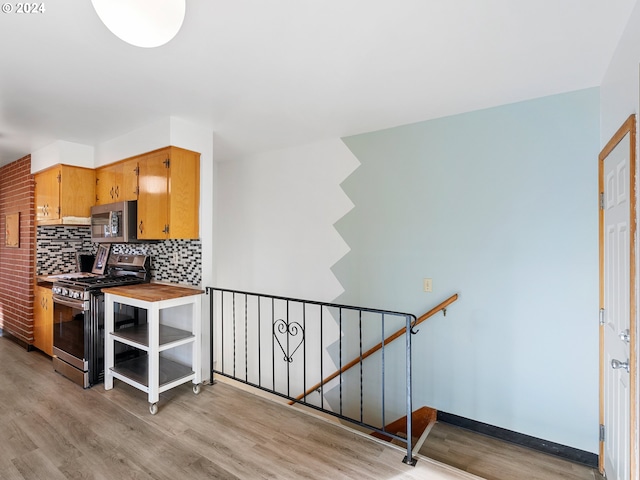 kitchen featuring light wood finished floors, appliances with stainless steel finishes, decorative backsplash, and light countertops