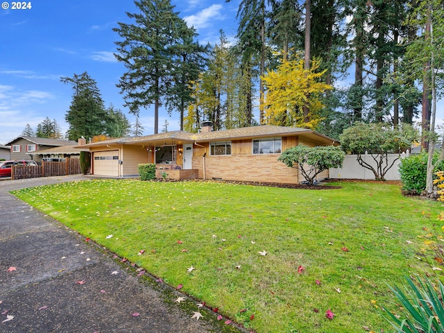 single story home with aphalt driveway, an attached garage, fence, and a front yard