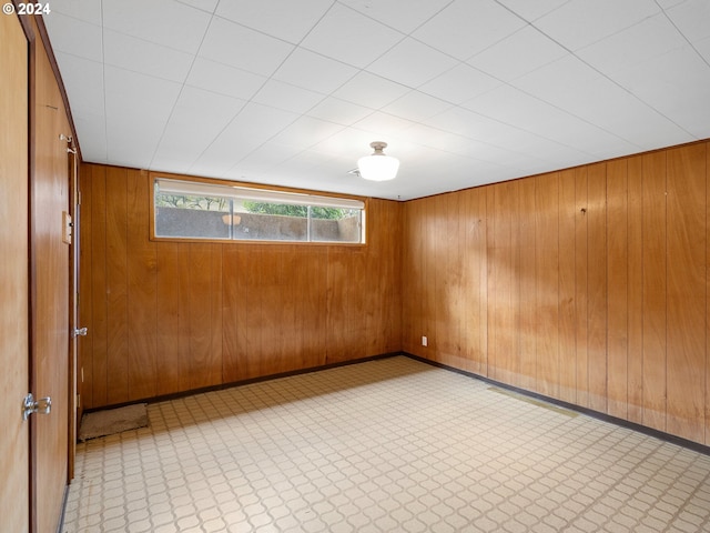 spare room featuring light floors, wood walls, and baseboards