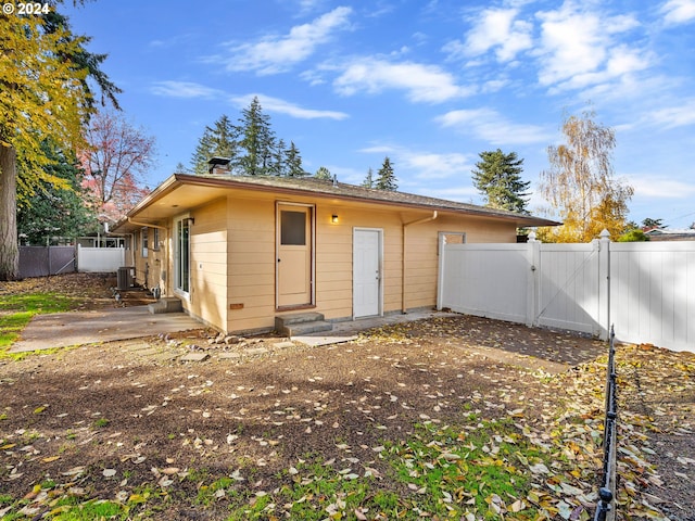 back of property featuring entry steps, a patio, a chimney, a gate, and fence