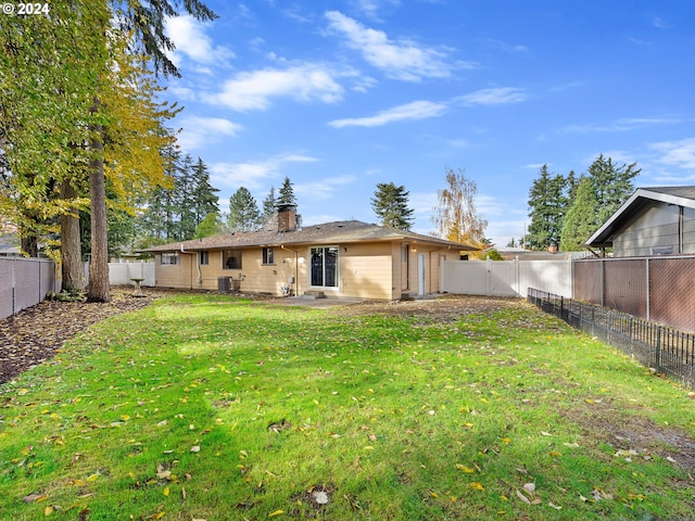 rear view of property featuring cooling unit and a yard