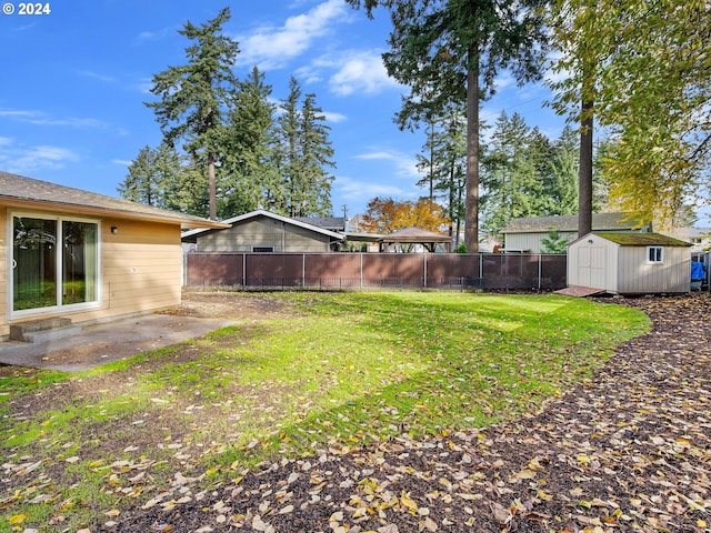 view of yard featuring an outbuilding, a patio area, a fenced backyard, and a storage unit