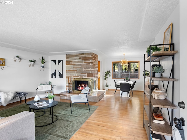 living room featuring a textured ceiling, a fireplace, a chandelier, and wood finished floors