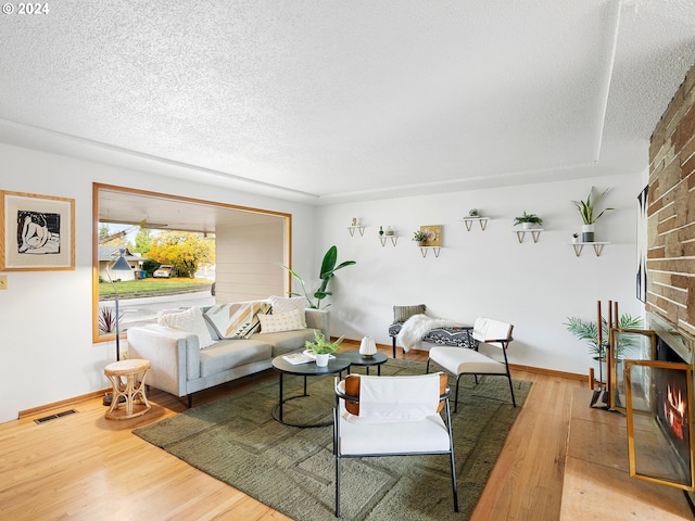 living room featuring visible vents, a fireplace, a textured ceiling, and wood finished floors