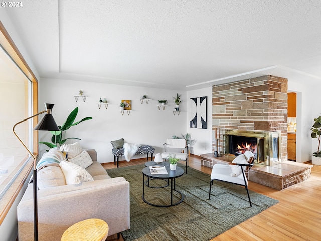 living room featuring a fireplace, a textured ceiling, and wood finished floors