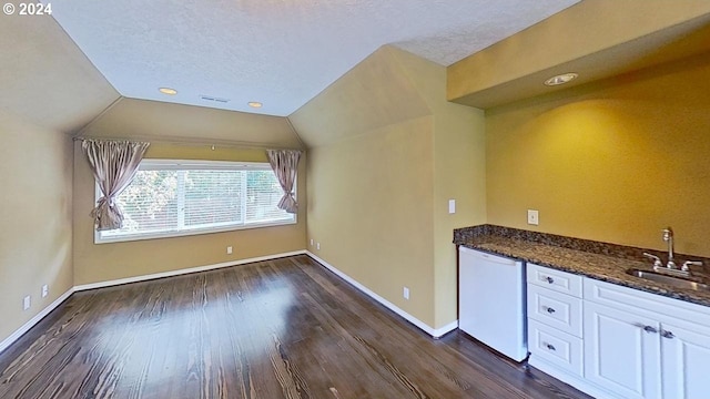 interior space featuring sink, lofted ceiling, dark hardwood / wood-style flooring, and a textured ceiling