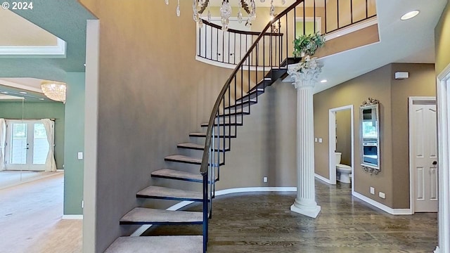 stairway featuring a notable chandelier and ornate columns