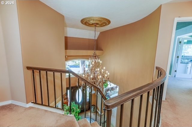 stairway featuring an inviting chandelier and carpet