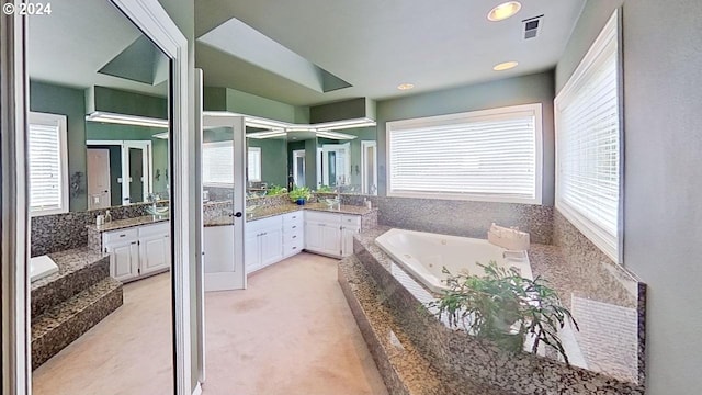 bathroom with a relaxing tiled tub and vanity