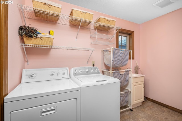 washroom featuring washing machine and dryer, light tile patterned floors, and cabinets