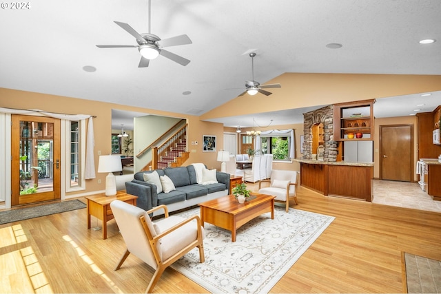 living room featuring ceiling fan with notable chandelier, lofted ceiling, and light hardwood / wood-style floors