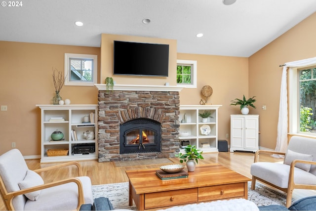 living room with light hardwood / wood-style flooring, a fireplace, and a healthy amount of sunlight