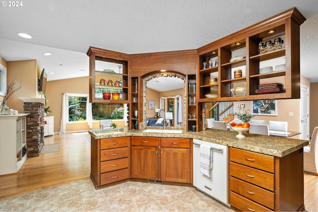 kitchen featuring a textured ceiling, vaulted ceiling, sink, light hardwood / wood-style flooring, and kitchen peninsula