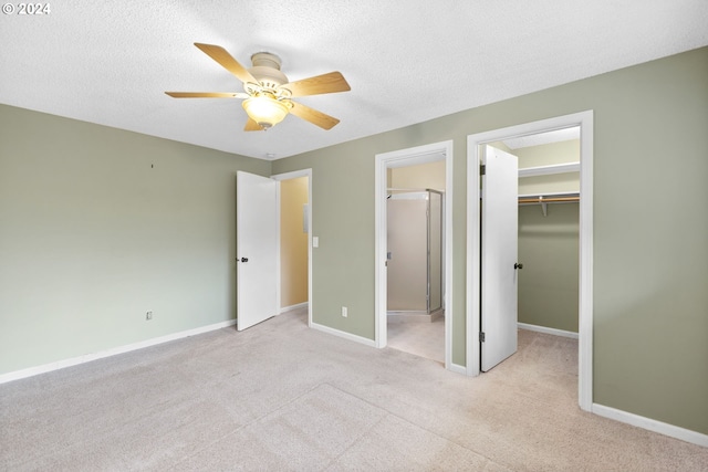 unfurnished bedroom featuring a textured ceiling, connected bathroom, ceiling fan, a closet, and a spacious closet