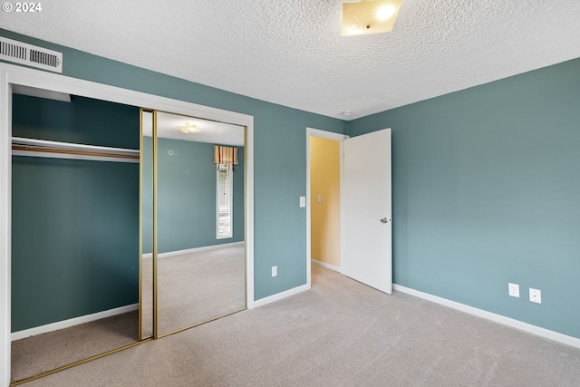 unfurnished bedroom featuring a textured ceiling, carpet floors, and a closet