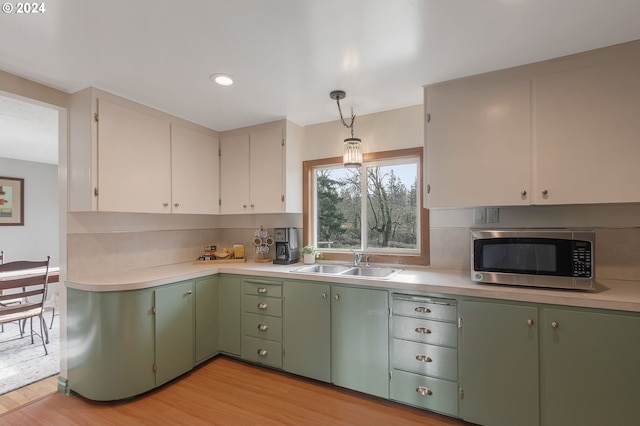 kitchen featuring sink, decorative light fixtures, white cabinets, light hardwood / wood-style floors, and green cabinets