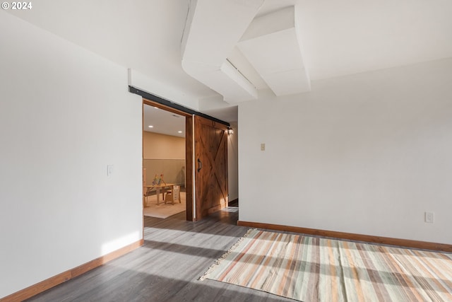 spare room featuring a barn door and dark hardwood / wood-style floors