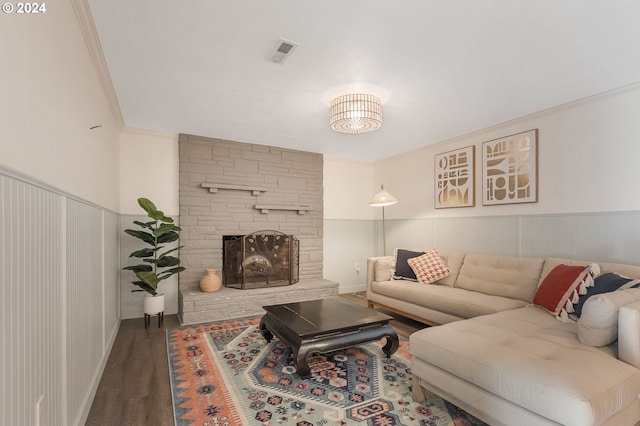 living room with a stone fireplace, wood-type flooring, and ornamental molding