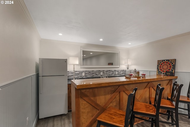 kitchen featuring kitchen peninsula, wood-type flooring, white refrigerator, and crown molding