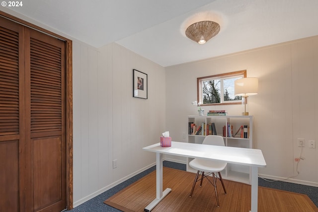 carpeted office space featuring wooden walls