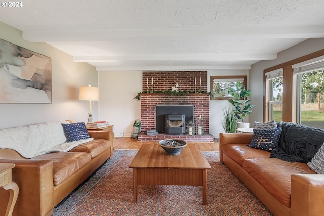 living room featuring beamed ceiling, a wood stove, dark wood-type flooring, and a textured ceiling