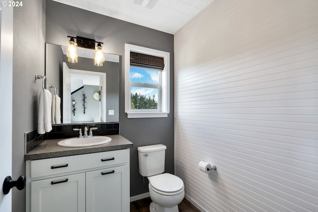 bathroom featuring vanity, toilet, and tile walls