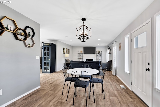 dining room featuring a notable chandelier, a healthy amount of sunlight, and wood-type flooring